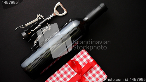 Image of Red wine bottle, corkscrew and boxed christmas gift