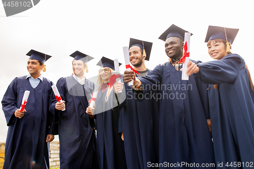 Image of happy students in mortar boards with diplomas