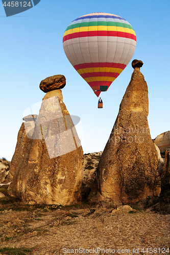 Image of Hot air baloon flying over spectacular stone cliffs in Cappadocia