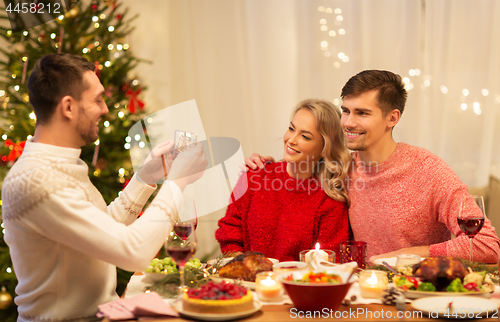 Image of happy friends photographing at christmas dinner