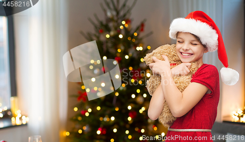 Image of girl in santa hat with teddy bear on christmas