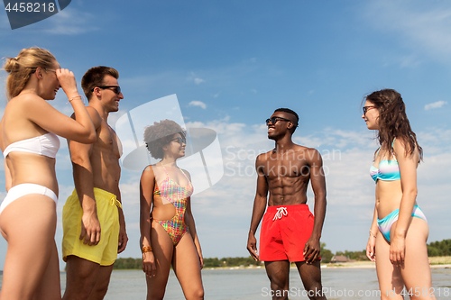 Image of happy friends hugging on summer beach