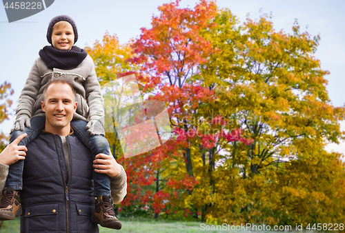 Image of happy father carrying son over autumn park