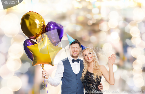 Image of happy couple with party caps and balloons