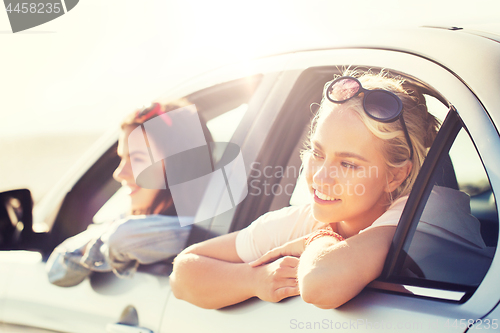 Image of happy teenage girls or women in car at seaside