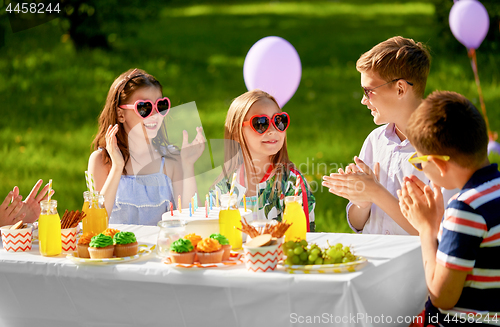 Image of happy kids with cake on birthday party in summer