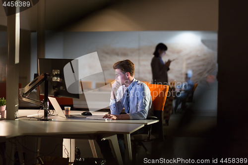 Image of man working on computer in dark office