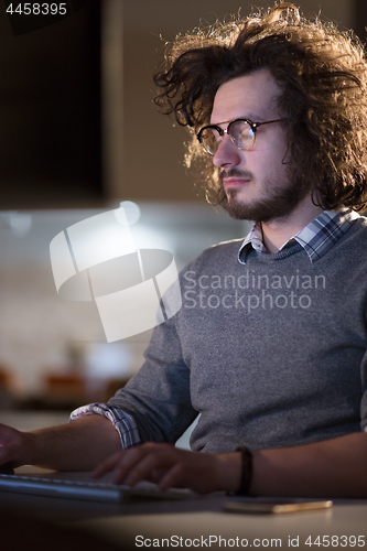 Image of man working on computer in dark office