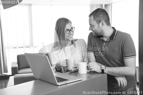 Image of couple drinking coffee and using laptop at home