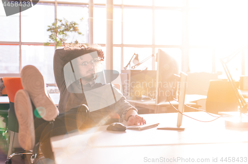 Image of businessman sitting with legs on desk