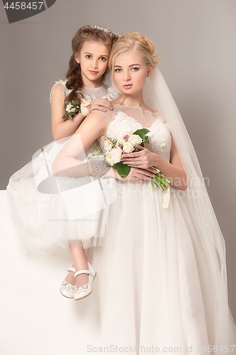 Image of Little pretty girls with flowers dressed in wedding dresses