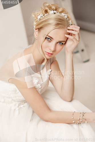 Image of Bride in beautiful dress standing indoors in white studio interior like at home. Trendy wedding style shot. Young attractive caucasian model like a bride tender looking.