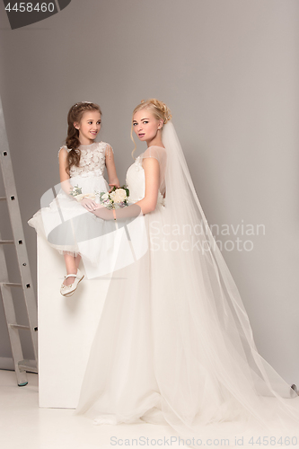 Image of Little pretty girls with flowers dressed in wedding dresses