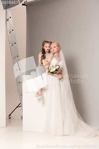 Image of Little pretty girls with flowers dressed in wedding dresses