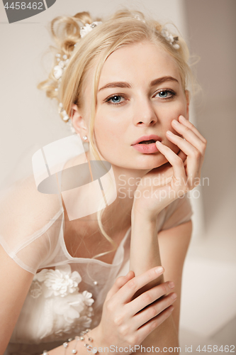 Image of Bride in beautiful dress standing indoors in white studio interior like at home. Trendy wedding style shot. Young attractive caucasian model like a bride tender looking.