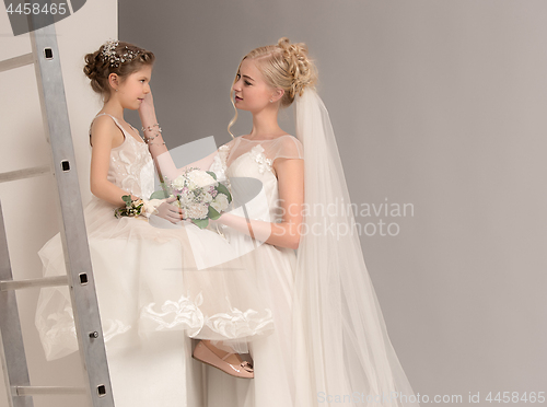 Image of Little pretty girls with flowers dressed in wedding dresses