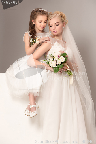 Image of Little pretty girls with flowers dressed in wedding dresses