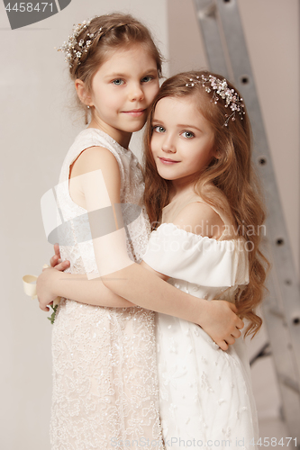 Image of Little pretty girls with flowers dressed in wedding dresses