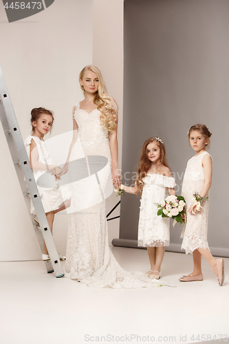 Image of Little pretty girls with flowers dressed in wedding dresses