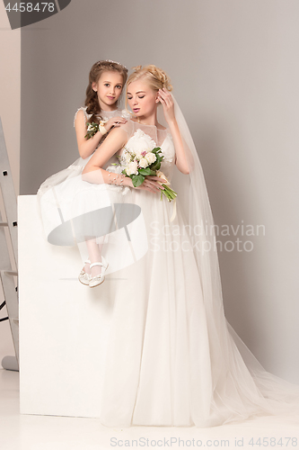 Image of Little pretty girls with flowers dressed in wedding dresses