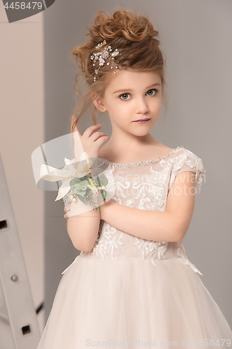 Image of Little pretty girl with flowers dressed in wedding dresses