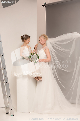 Image of Little pretty girls with flowers dressed in wedding dresses