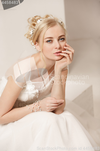 Image of Bride in beautiful dress standing indoors in white studio interior like at home. Trendy wedding style shot. Young attractive caucasian model like a bride tender looking.