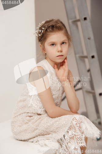 Image of Little pretty girl with flowers dressed in wedding dresses