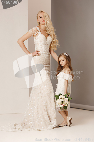 Image of Little pretty girls with flowers dressed in wedding dresses