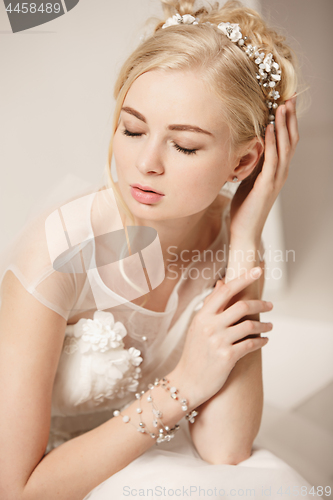 Image of Bride in beautiful dress standing indoors in white studio interior like at home. Trendy wedding style shot. Young attractive caucasian model like a bride tender looking.