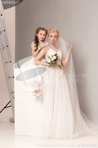 Image of Little pretty girls with flowers dressed in wedding dresses