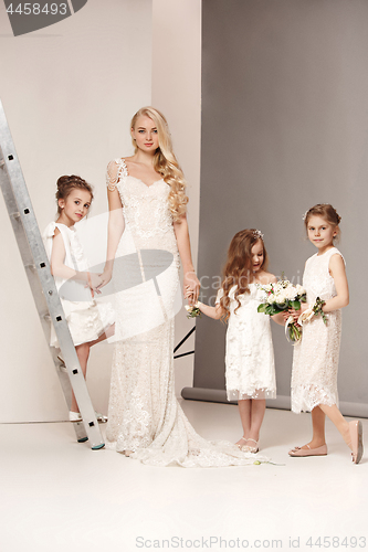 Image of Little pretty girls with flowers dressed in wedding dresses