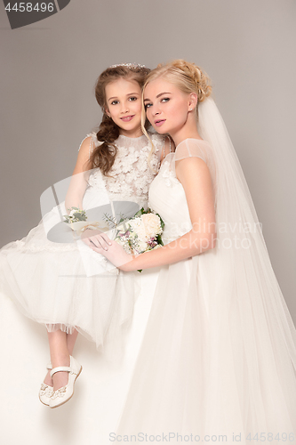 Image of Little pretty girls with flowers dressed in wedding dresses