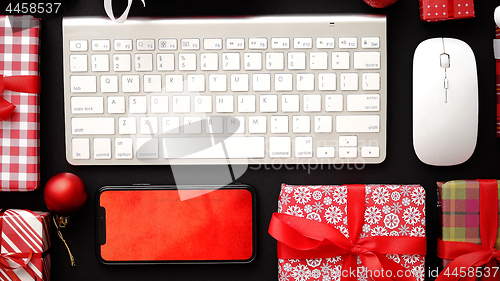 Image of Computer keyboard, modern smartphone, mouse and christmas boxed gifts