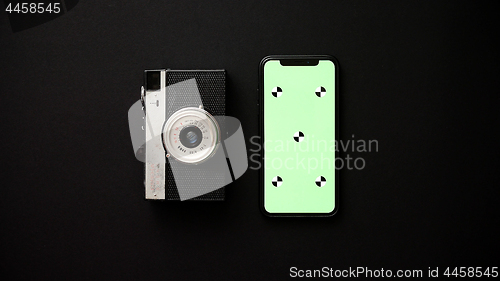 Image of Old retro film camera and modern smartphone on black background