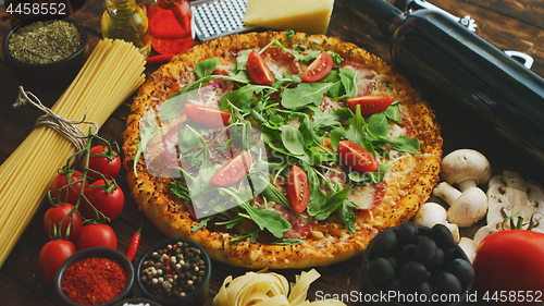 Image of Italian food background with pizza, raw pasta and vegetables on wooden table