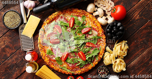 Image of Italian food background with pizza, raw pasta and vegetables on wooden table