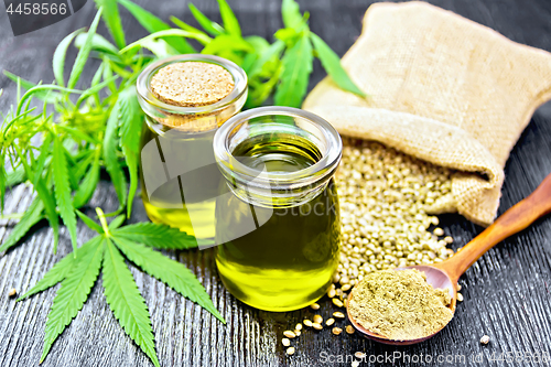 Image of Oil hemp in two jars and flour in spoon on board