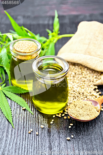 Image of Oil hemp in two jars and flour in spoon on dark board