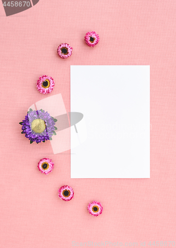 Image of Flowers and white sheet of paper on pink canvas