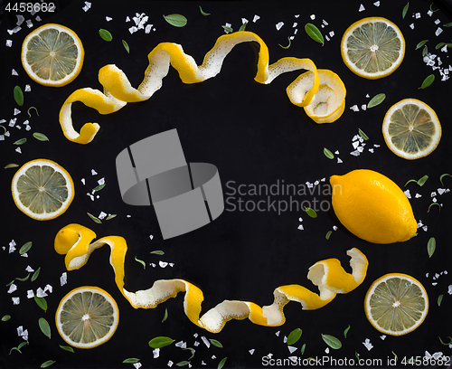 Image of Frame made of lemons and salt on black background