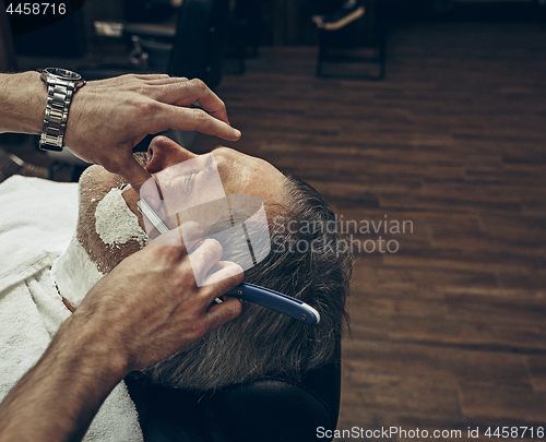 Image of Close-up side top view handsome senior bearded caucasian man getting beard grooming in modern barbershop.