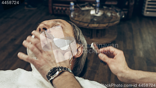 Image of Close-up side top view handsome senior bearded caucasian man getting beard grooming in modern barbershop.