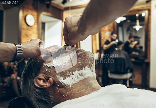 Image of Close-up side top view handsome senior bearded caucasian man getting beard grooming in modern barbershop.