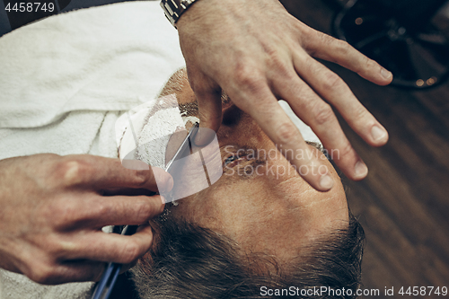 Image of Close-up side top view handsome senior bearded caucasian man getting beard grooming in modern barbershop.