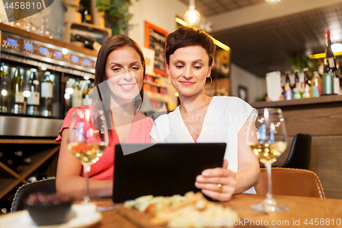 Image of women with tablet pc at wine bar or restaurant