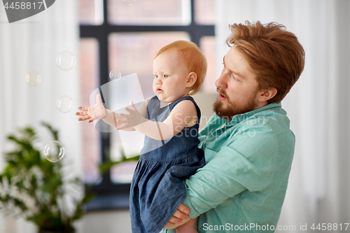 Image of father and baby daughter with soap bubbles at home