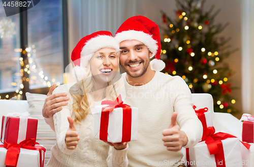 Image of happy couple with christmas gifts and thumbs up