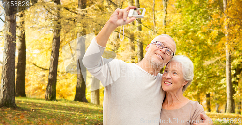 Image of senior couple taking selfie in autumn park