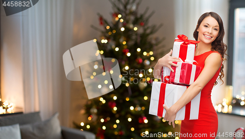 Image of smiling woman with christmas gifts at home